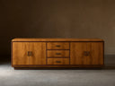 Front view of the Palma Media Console, showing light brown cerajeira wood veneer with cathedral graining, dark trim, and aged bronze hardware.