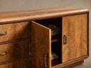 Close-up of the Palma Media Console, rich brown cerajeira wood with cathedral graining, rounded top, aged bronze handles, open cabinet door revealing interior.